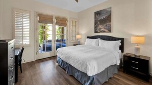 A bedroom with a bed, two bedside tables, a ceiling fan, and a painting on the wall. - Heritage Hideaway | 2BR Legacy Villa (La Quinta)