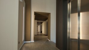 A long, narrow hallway with a tiled floor and a series of doors on one side. - Loft Trevisan • Elegant loft with private garage (Bra)