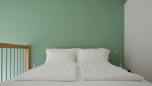 A neatly made bed with white linens in a room with green walls. - Loft Trevisan • Elegant loft with private garage (Bra)