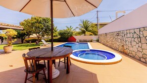 Ein Garten mit Pool, einem Esstisch und Stühlen.