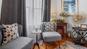 En stue med to grå sofaer, et lille bord med en plante, en lampe og et billede i ramme på væggen.