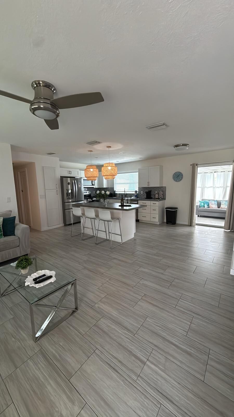 A spacious living area with a modern kitchen, a dining area, and a ceiling fan.