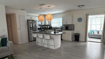 A spacious living area with a modern kitchen, a dining area, and a ceiling fan.
