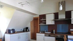 Uma cozinha compacta com armários brancos, bancada de madeira, fogão e pia.