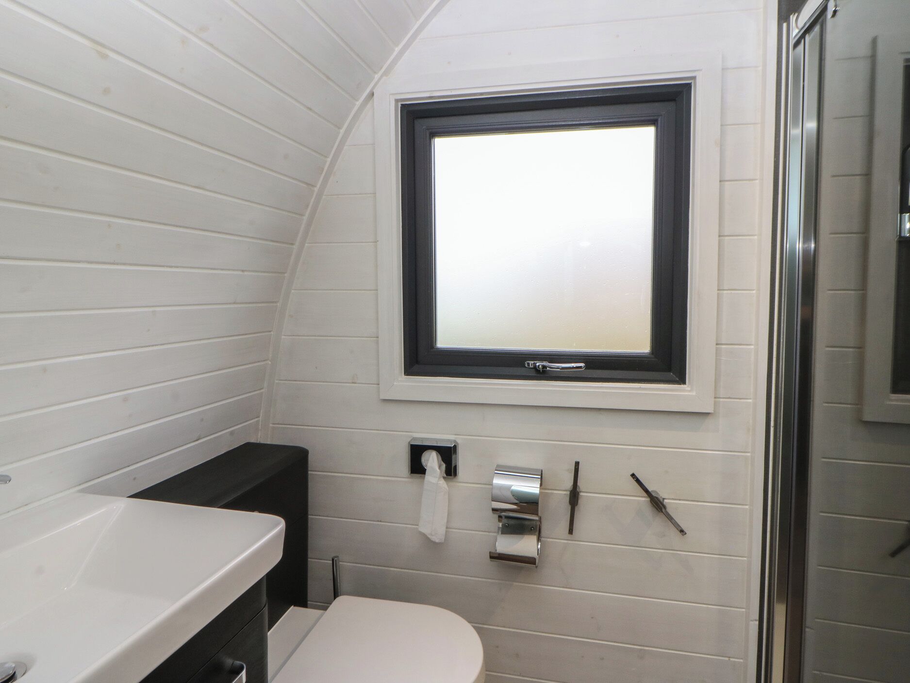 A compact bathroom with a toilet, sink, and window.