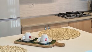 A modern kitchen with wooden cabinets, a white countertop, and a dining table with two white cups and a woven placemat. - Detached apartment in residence with swimming pool (Peschici)