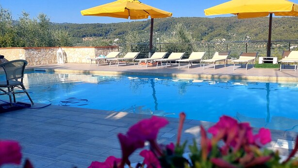 A pool area with lounge chairs and yellow umbrellas, surrounded by stone walls and a view of hills. - Detached apartment in residence with swimming pool (Peschici)