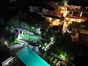 A nighttime view of a residential area with a swimming pool, a tennis court, and a well-lit balcony. - Detached apartment in residence with swimming pool (Peschici)