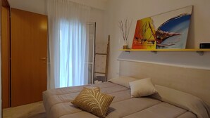 A bedroom with a bed, a painting, a shelf, and a door. - Detached apartment in residence with swimming pool (Peschici)