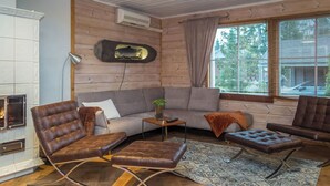 Uma sala de estar aconchegante com um sofá, duas poltronas de couro, uma mesinha e uma lareira.