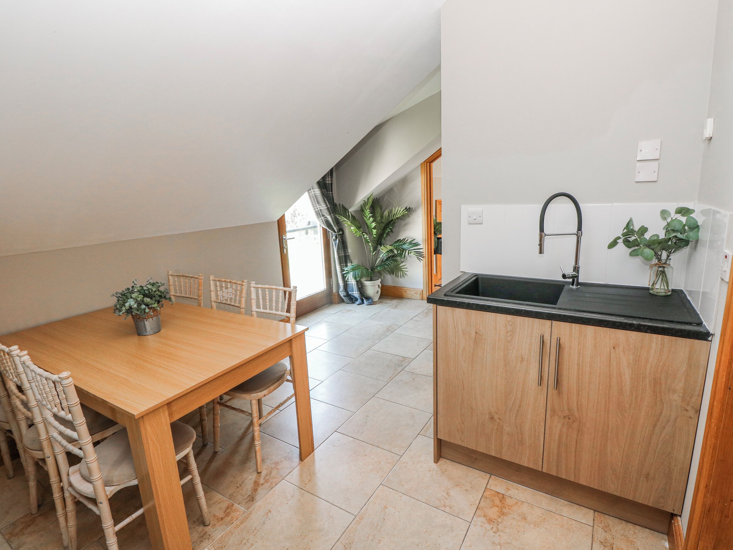 Una cocina compacta con una mesa y sillas de madera, una encimera negra y un fregadero.