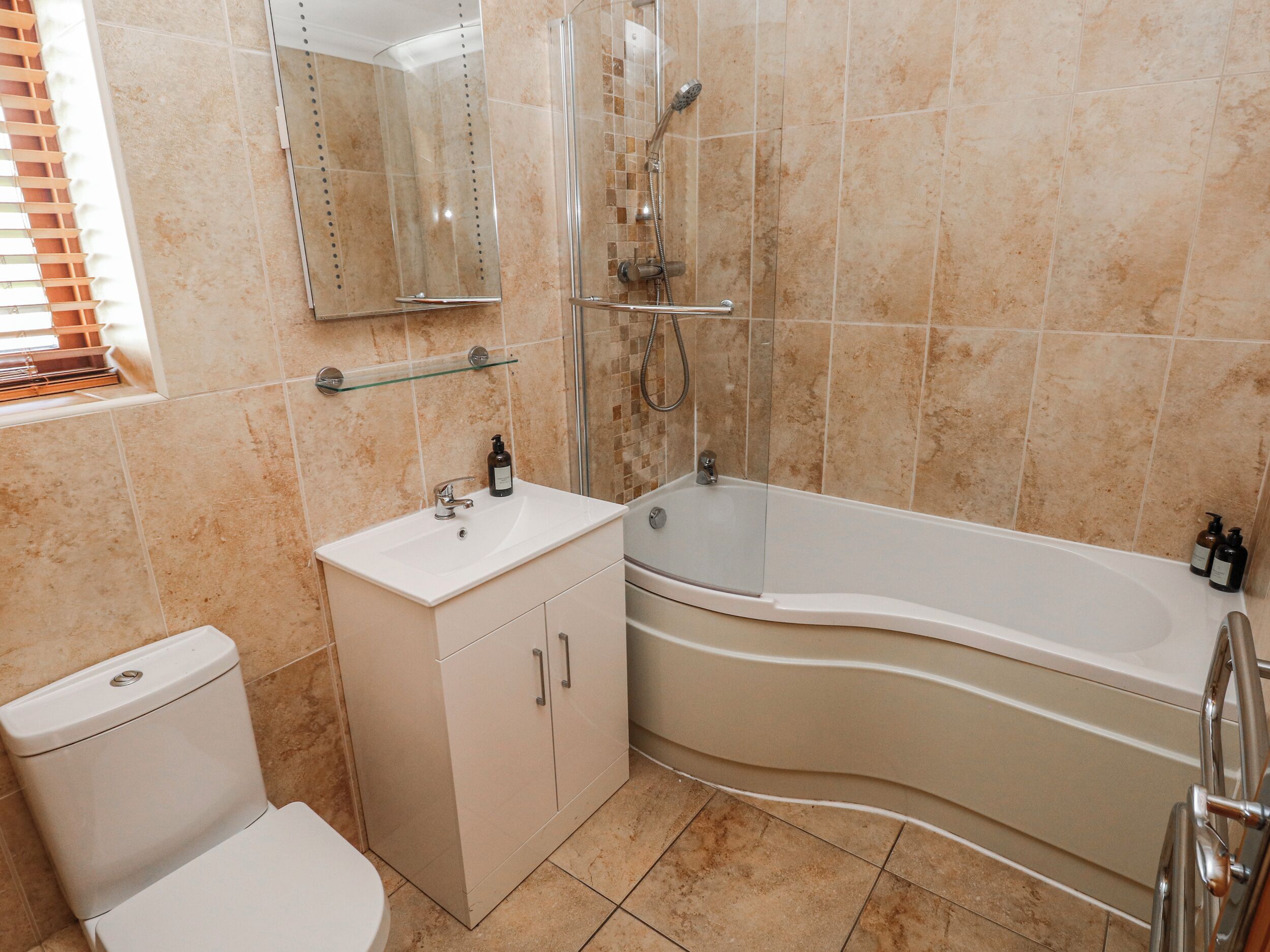 Un baño con inodoro, lavamanos, espejo, ducha y bañera.