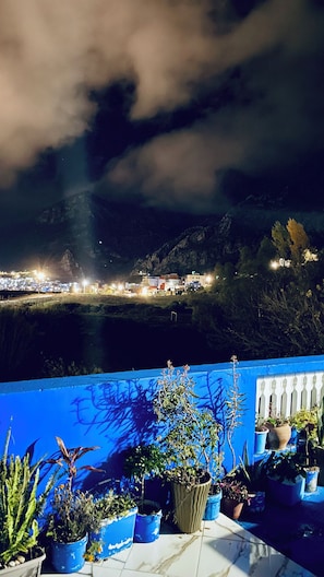 A night view of a coastal town with illuminated buildings and a mountain backdrop. - Spacious apartment with terrace - 2 bedrooms, 5 beds, fully equipped (Chefchaouen)