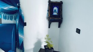 Ein Zimmer mit einem blauen Sofa, einem kleinen Tisch mit Topfpflanze und einem an der Wand befestigten Bilderrahmen.