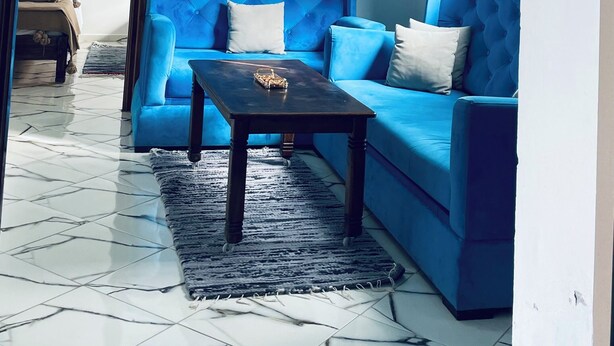 Ein Wohnzimmer mit blauem Sofa, einem Couchtisch und einer Pendelleuchte.