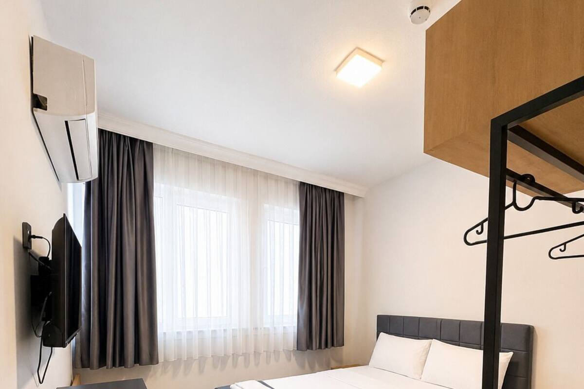 Une chambre d’hôtel moderne équipée d’un lit, d’un bureau, d’une télévision et d’un miroir.