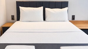 A bed with a dark headboard, two bedside tables, and two wall-mounted lights.