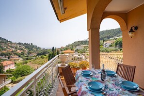 Un balcó amb una taula preparada per dinar, amb vista a un poble situat a la valla.