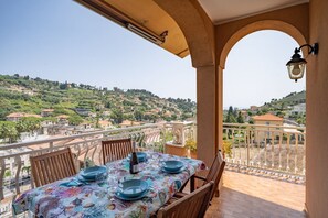 Ein Balkon mit Esstisch, mit Blick auf eine Stadt am Hang.