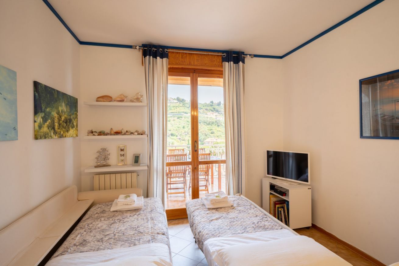 Een kamer met twee bedden, een televisie, een plank met decoratieve objecten en uitzicht op het omliggende landschap.