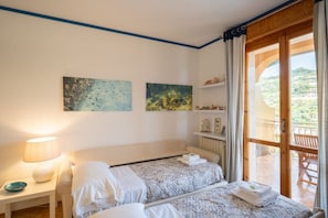 A bedroom with two beds, a nightstand, a lamp, and a view of the outdoors. - The apartment is located in an area of ​​Bordighera surrounded by greenery, the perfect solution for a relaxing holiday, with all the main comforts!The private parking in the garage, the shared outdoor swimming pool, the large covered terrace with ou (Bordighera)
