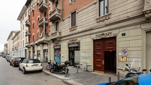 A street with parked cars and a building with a closed shop. - GuestHost - Cozy and quiet apartment in Milan! (Milano)