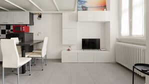 A modern kitchen with white cabinets, a red microwave, and a dining area with white chairs. - GuestHost - Cozy and quiet apartment in Milan! (Milano)