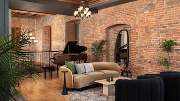 Un salón espacioso con pared de ladrillo, un piano de cola, un sofá y una mesa de centro.