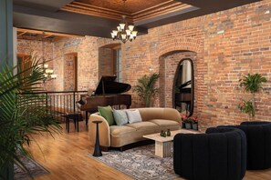 A spacious living area with a brick wall, a grand piano, a sofa, and a coffee table. - Tri Century Mill Suites (Carleton Place)