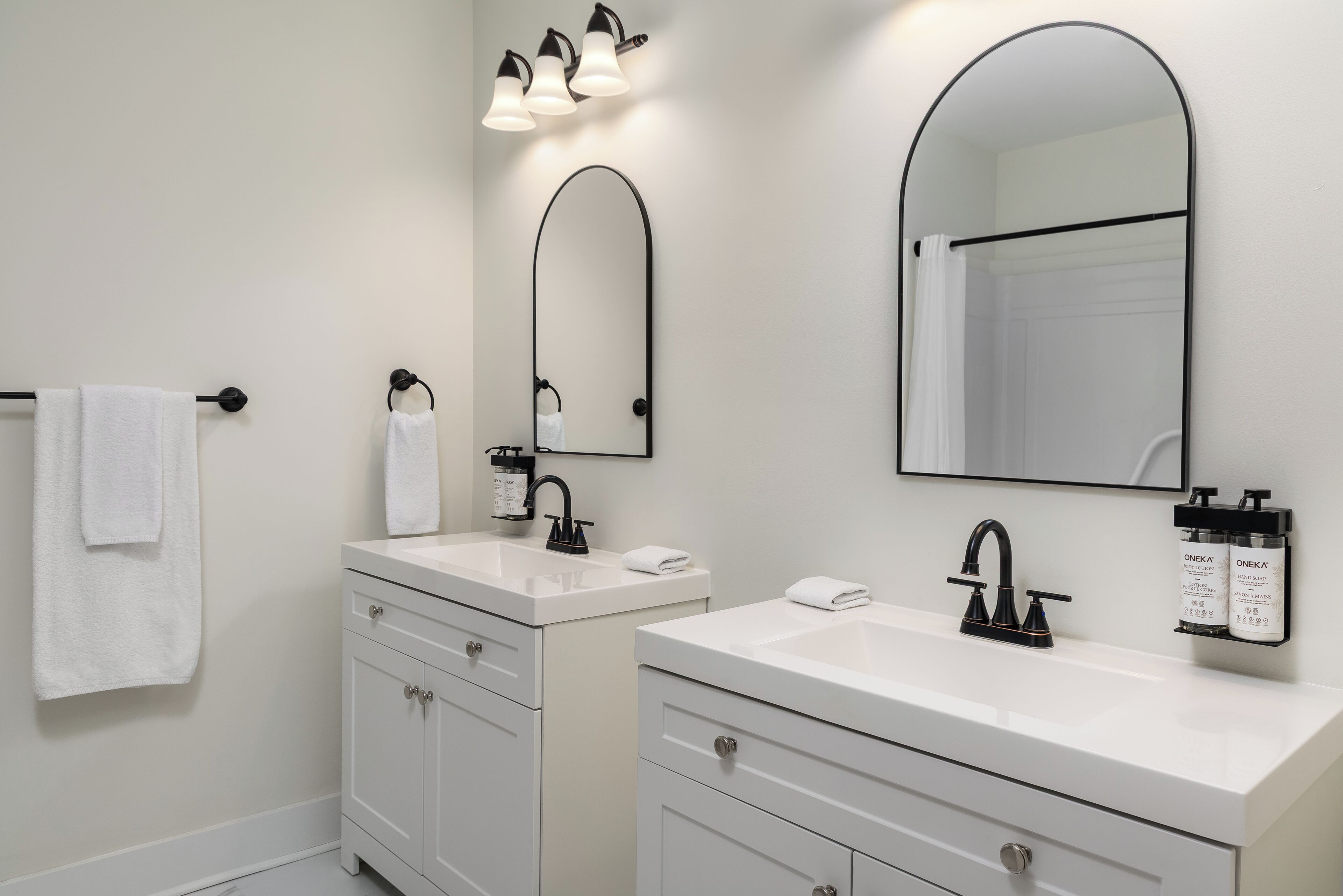 Un baño moderno con dos lavamanos, un espejo grande y un perchero para toallas.