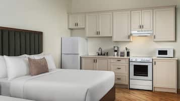 Una habitación de hotel con una cama, un kitchenette y piso de madera.
