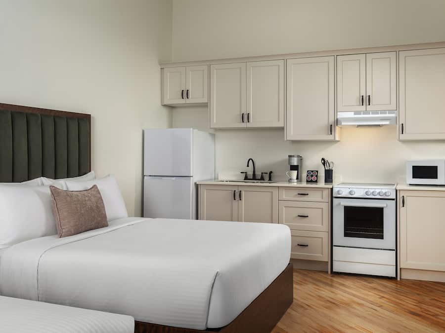 Una habitación de hotel con una cama, un kitchenette y piso de madera.