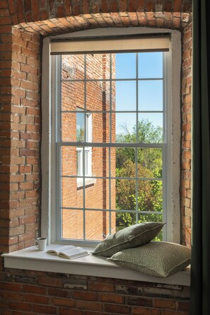 Una ventana con vista a un edificio de ladrillo y follaje exterior.