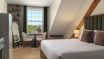 Une chambre d’hôtel avec un lit, un bureau, une chaise, une fenêtre et un mur en pierre.
