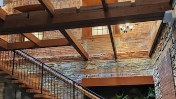 A spacious interior with exposed brick walls, a wooden staircase, and a modern chandelier.