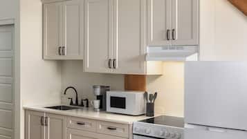 A kitchen with white cabinets, a coffee maker, a microwave, a stove, and a refrigerator.
