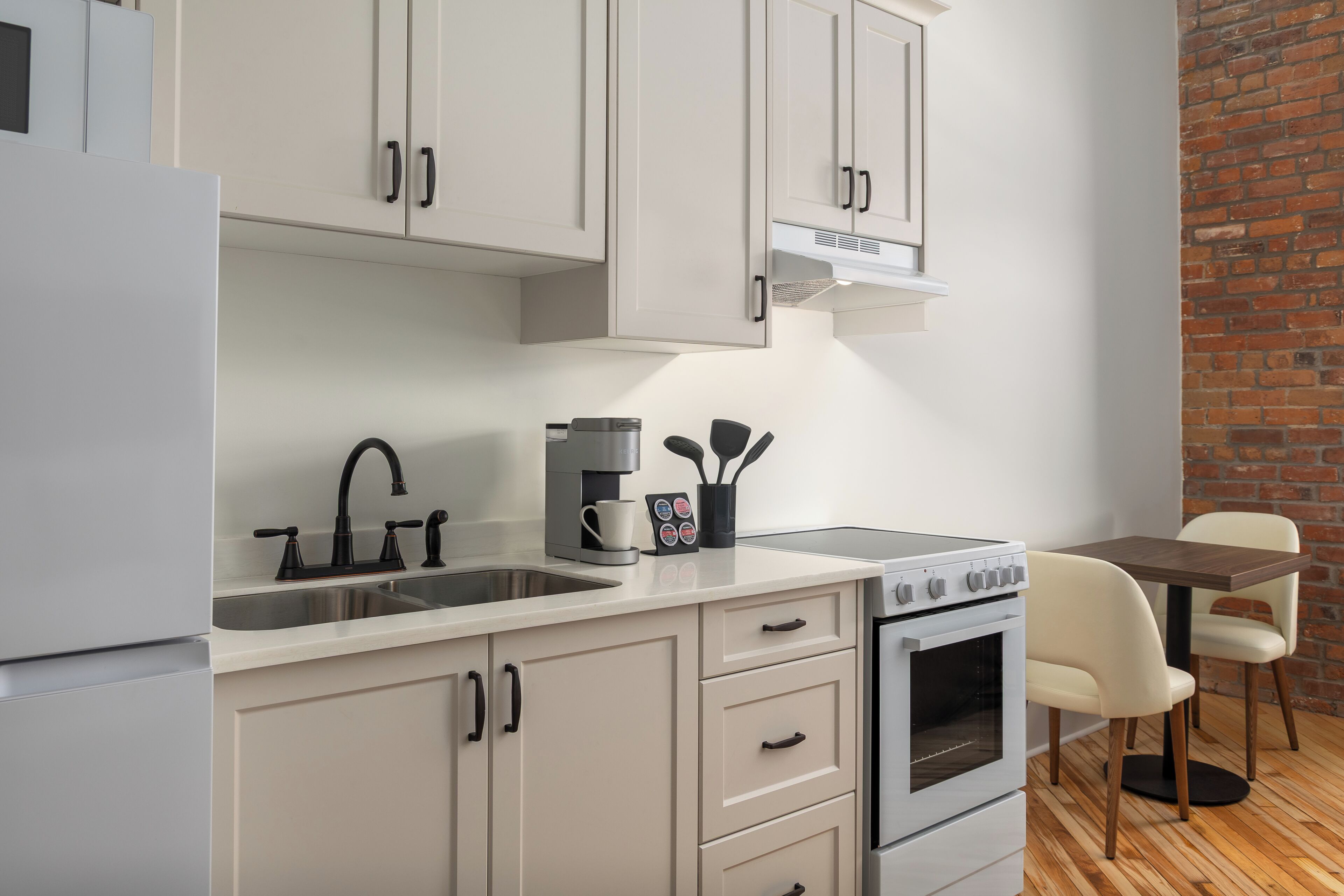 A compact kitchen with a sink, stove, and a coffee maker.