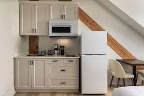 Una kitchenette compacta con microondas, refrigerador y detalles de madera.