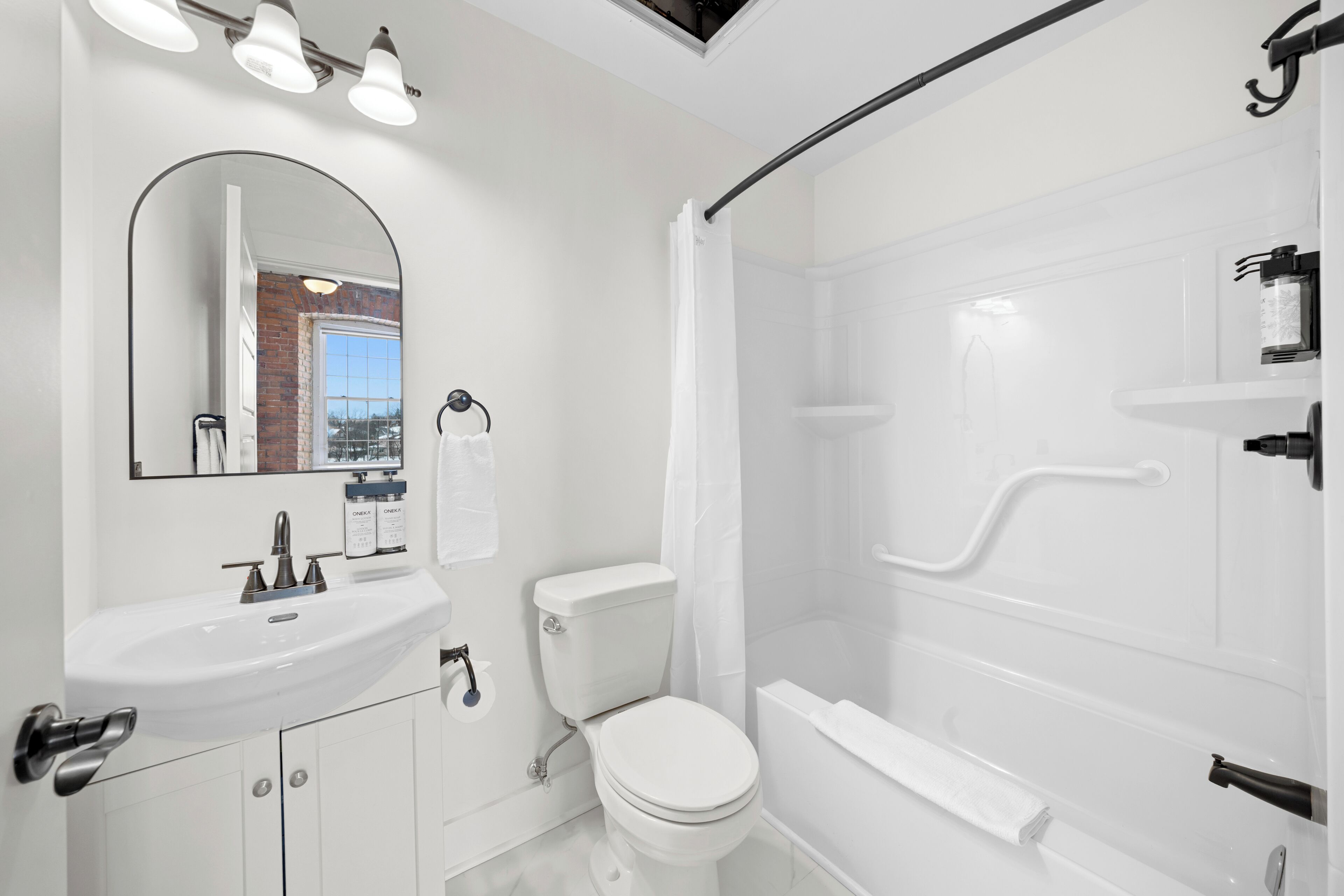 A modern bathroom with a white sink, toilet, and shower.