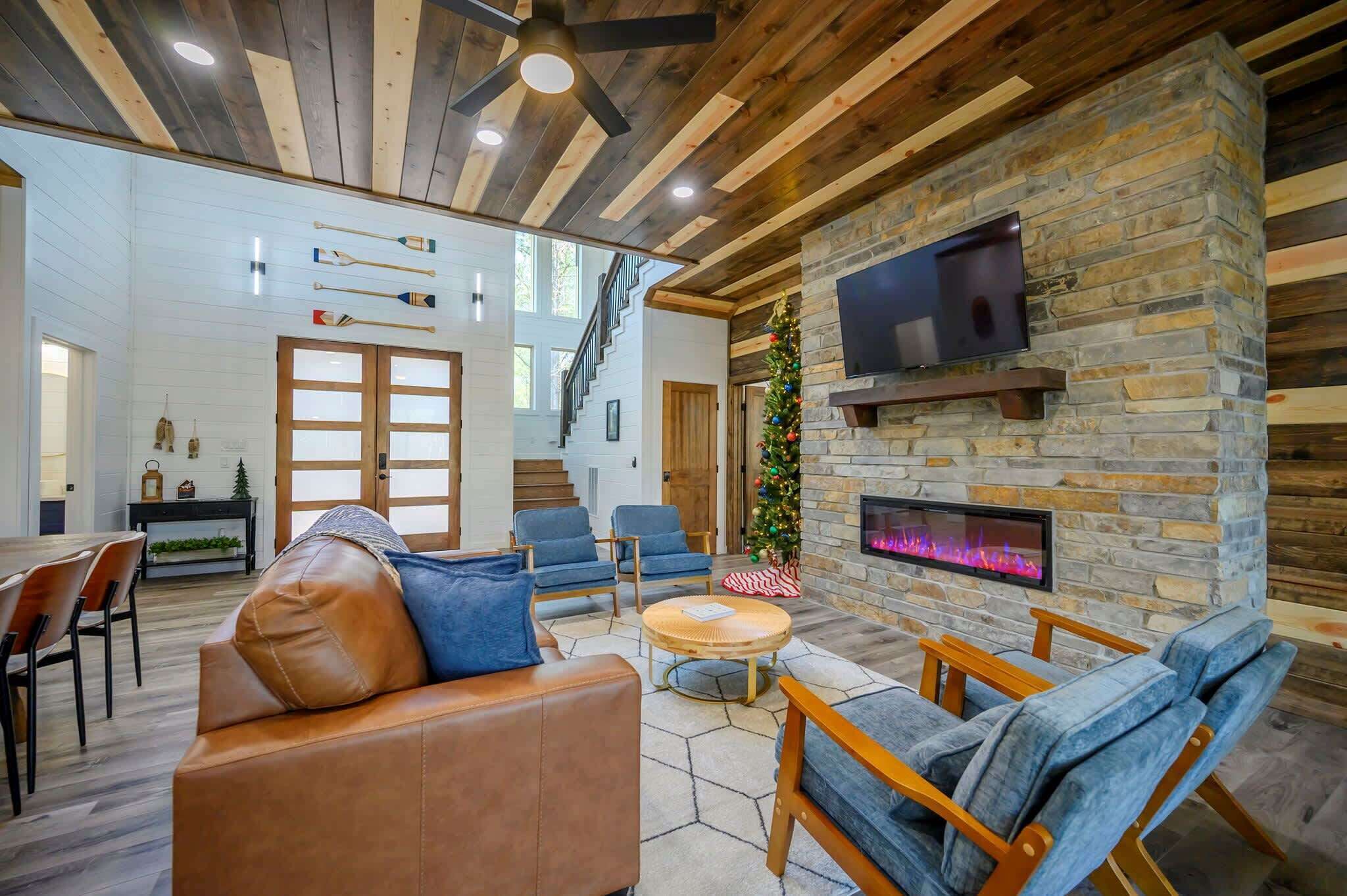 A modern living room with a stone fireplace, leather sofa, and blue chairs.