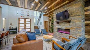 A modern living room with a stone fireplace, leather sofa, and blue chairs.