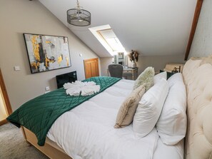 A bedroom with a bed, a desk, a chair, and a painting on the wall. - Rose Apartment - Gower (Swansea)