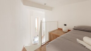 Un dormitorio con cama, mesita de noche, lámpara y vistas al exterior.