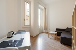 A modern living room with a sofa, a small table, a kettle, and a window with curtains. - The apartment is located in a stunning location, almost impossible to find! You are in the authentic heart of Milan, between Sant'Ambrogio district, renowned above all for the church of Santa Maria delle Grazie and the Catholic University and the charm o (Milano)