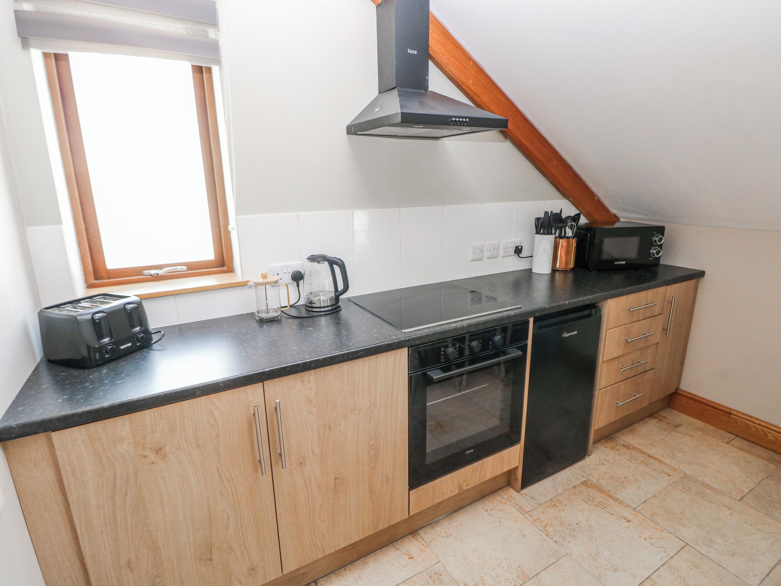 A kitchen with a toaster, coffee maker, microwave, oven, and wooden cabinets.