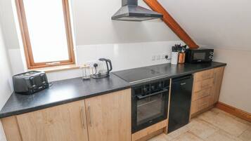 Una cocina con tostadora, cafetera, microondas, horno y armarios de madera.