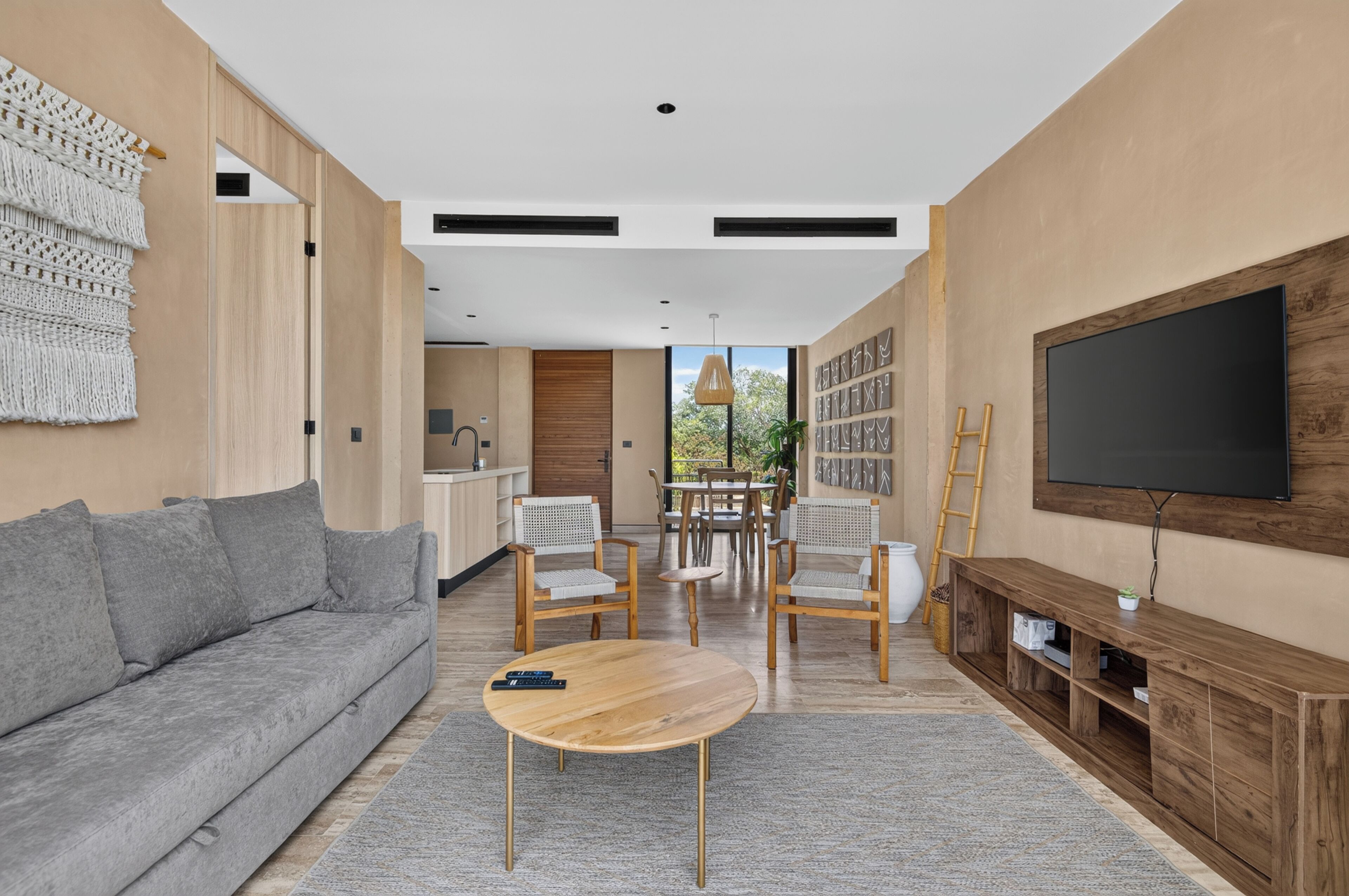 A modern living room with a grey sofa, wooden coffee table, and a TV on a wooden stand.
