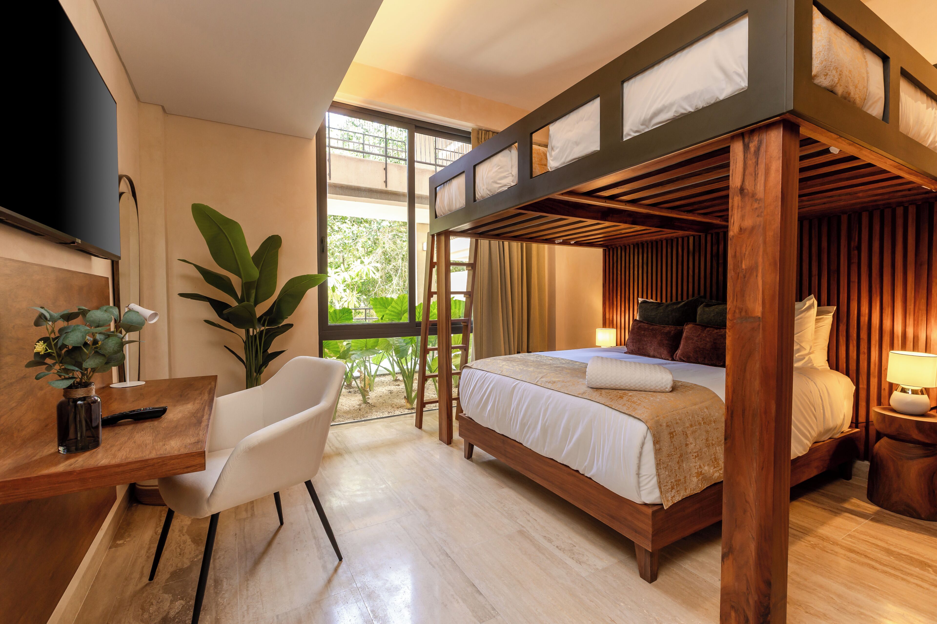 A bedroom with a bunk bed, a desk with a chair, a TV, and a large window with a view of greenery.