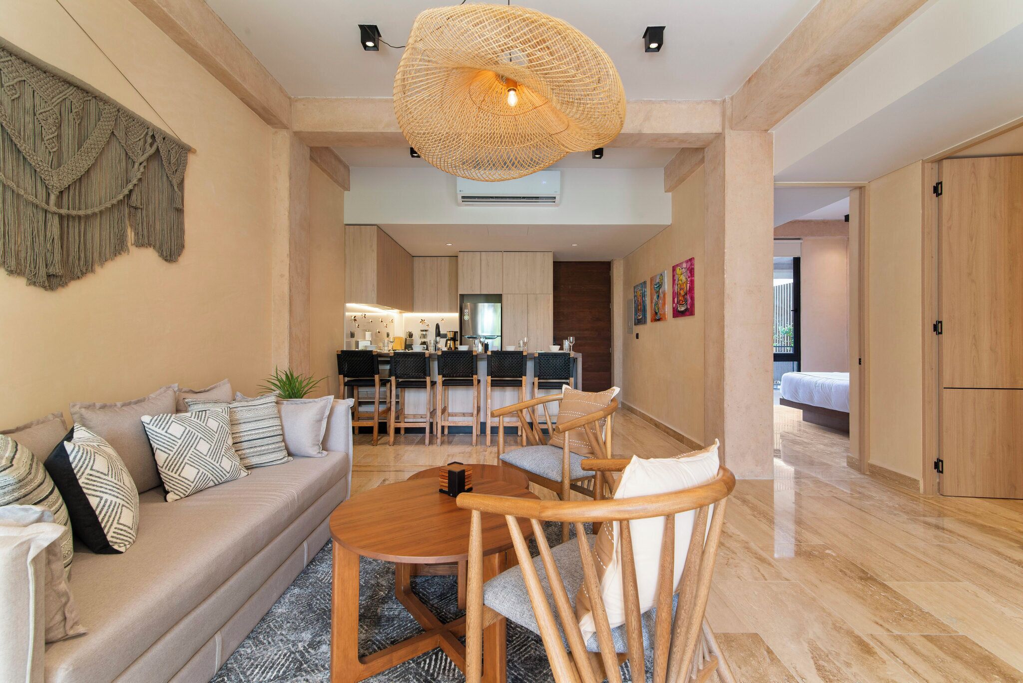 A modern living room with a sofa, dining table, and chairs. There is a kitchen in the background with a dining area.