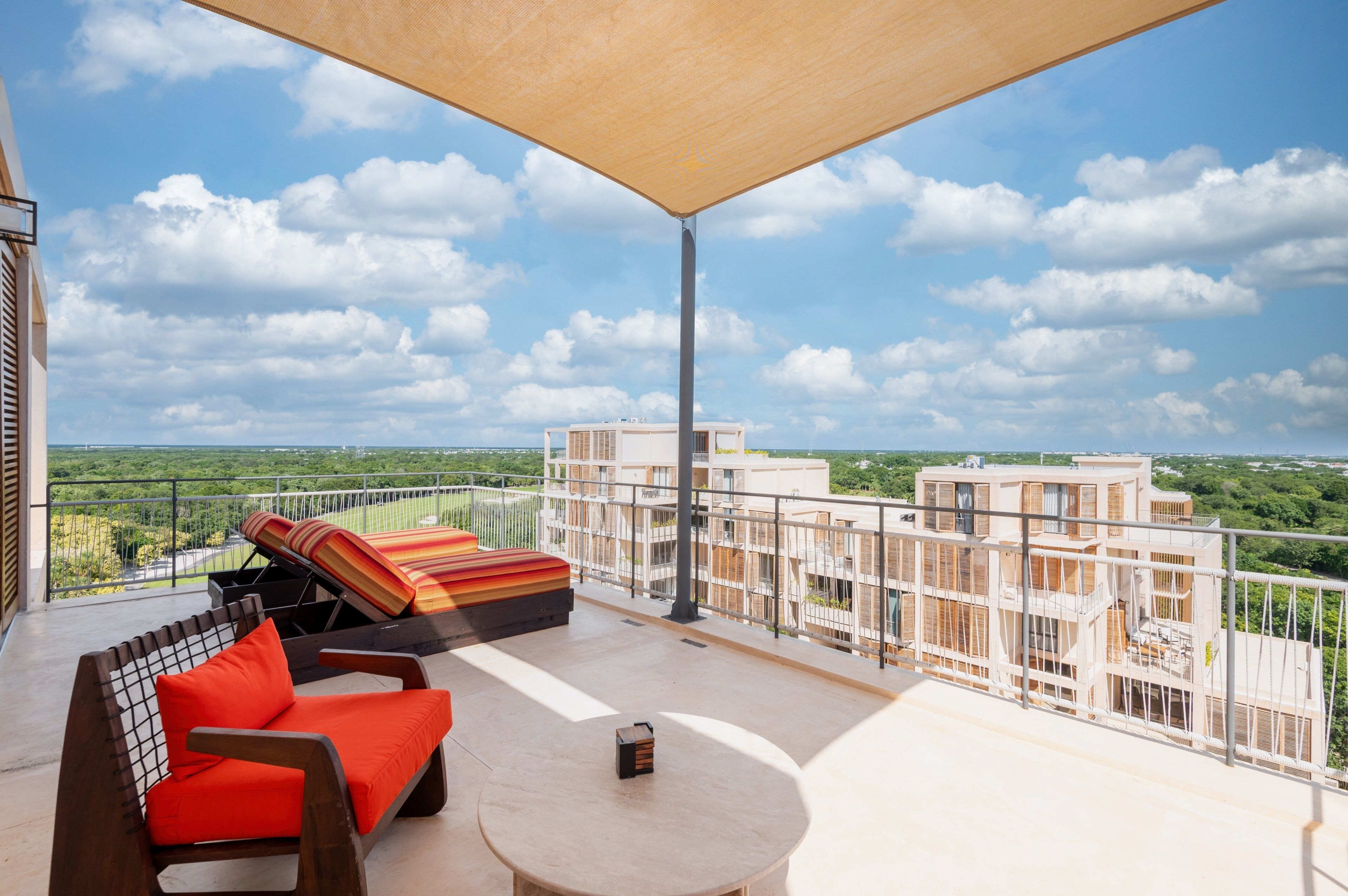 En balkon med udsigt over byen, en sofa, et bord og en parasol.